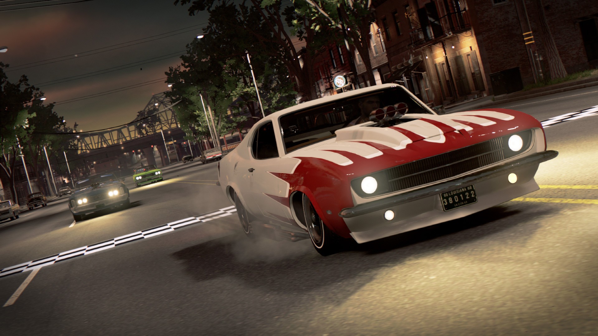 A white muscle car with red stripes drifts around a corner on a city street at dusk in Mafia III: Definitive Edition