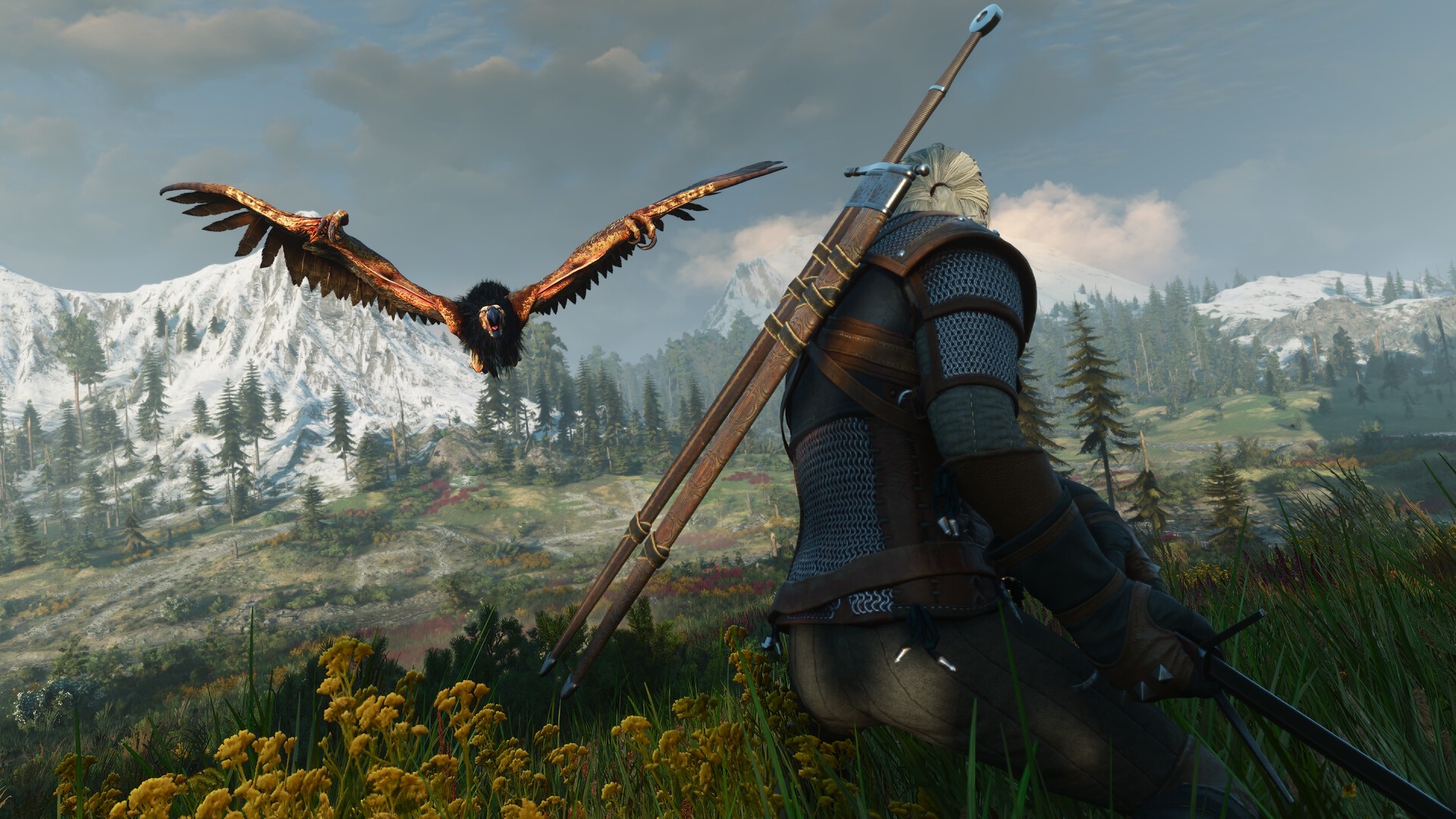 Geralt stands on a grassy hillside below snowy mountains as a large bird of prey flies past in The Witcher 3: Wild Hunt - Remastered