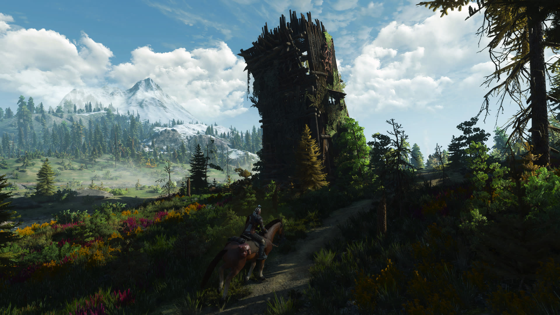 Geralt rides along a flowered hillside path below a ruined tower under a bright sky in The Witcher 3: Wild Hunt - Remastered on Nintendo Switch 2