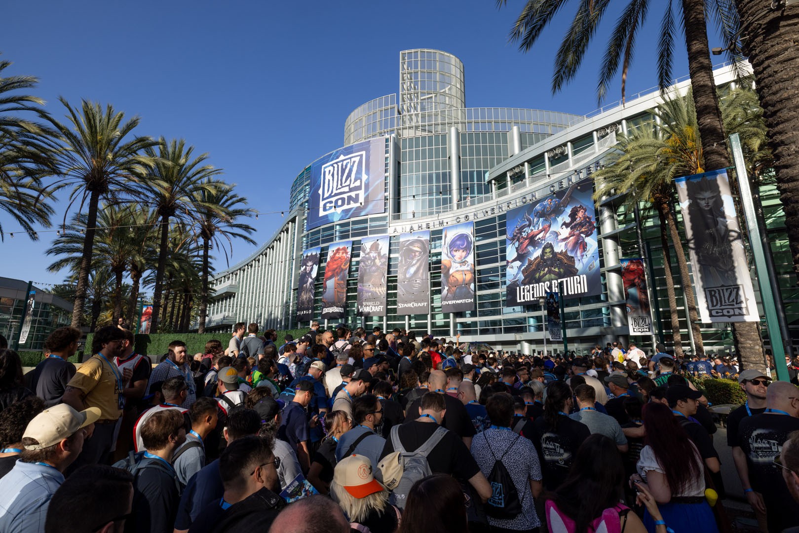 A large crowd gathers outside the Anaheim convention center under palm trees for BlizzCon 2026