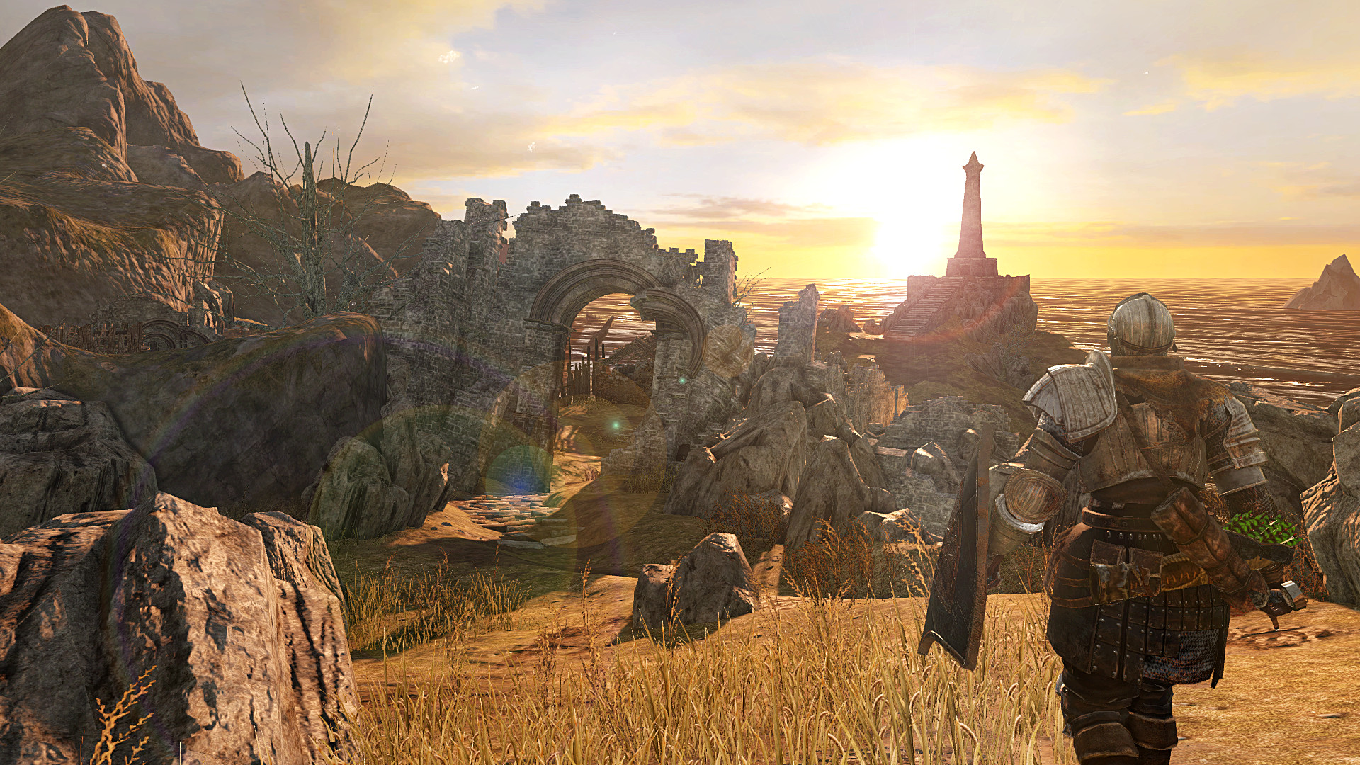 An armored character walks through tall grass toward a seaside lighthouse at sunset in Dark Souls II